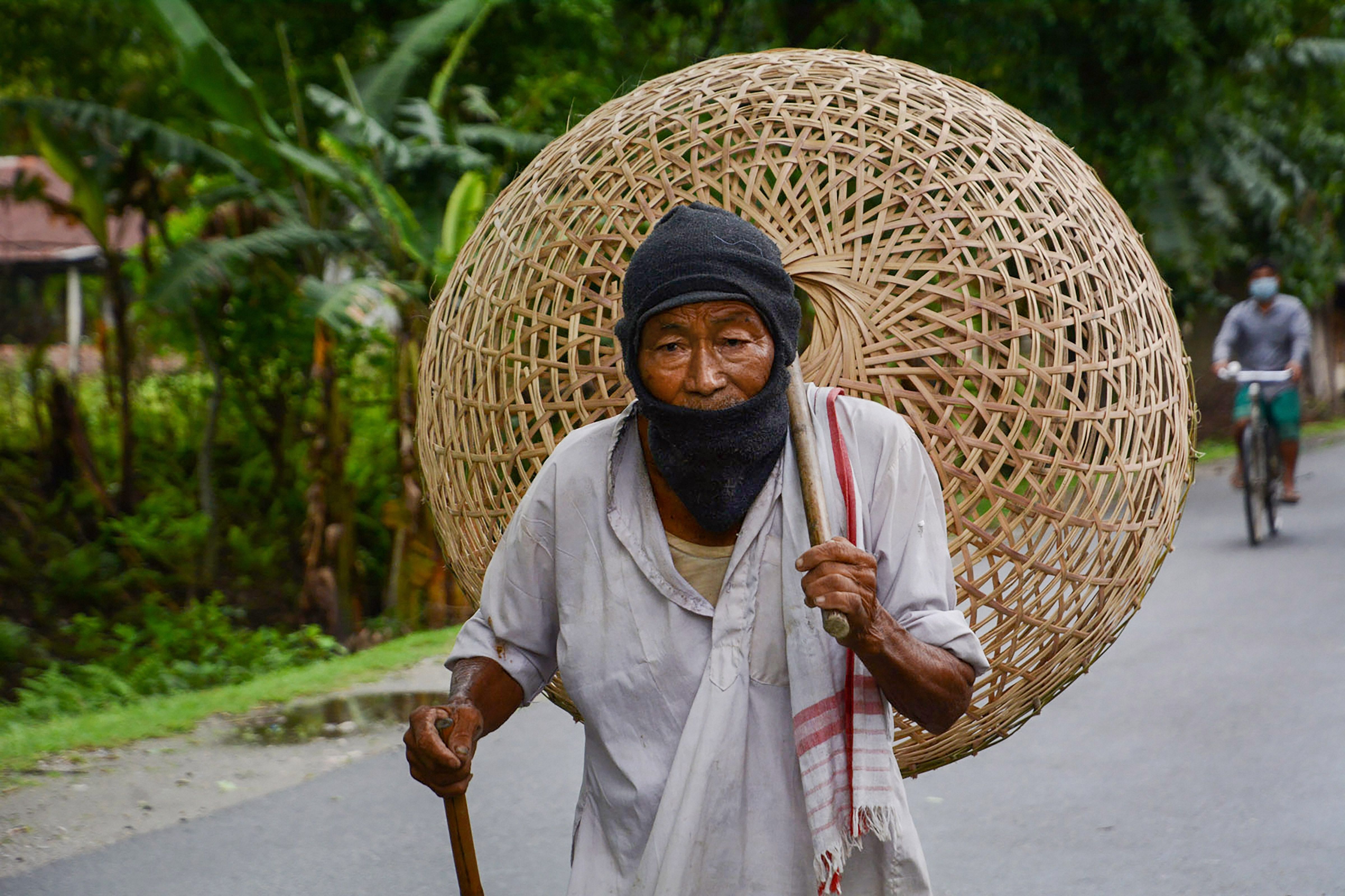 An elderly man walks to a market to sell bamboo baskets, during ongoing COVID-19 lockdown at Baganpara in Baksa district of Assam. (PTI photo)