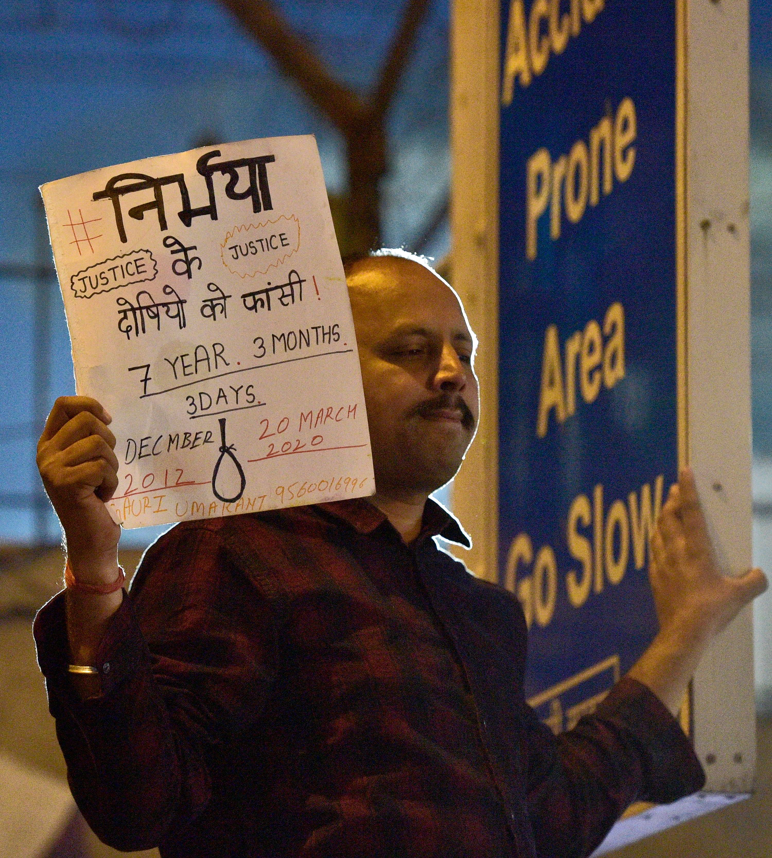 A man holds a placard outside Tihar jail during the execution of four men convicted of Nirbhaya rape and murder case, in New Delhi. (Credit: PTI)