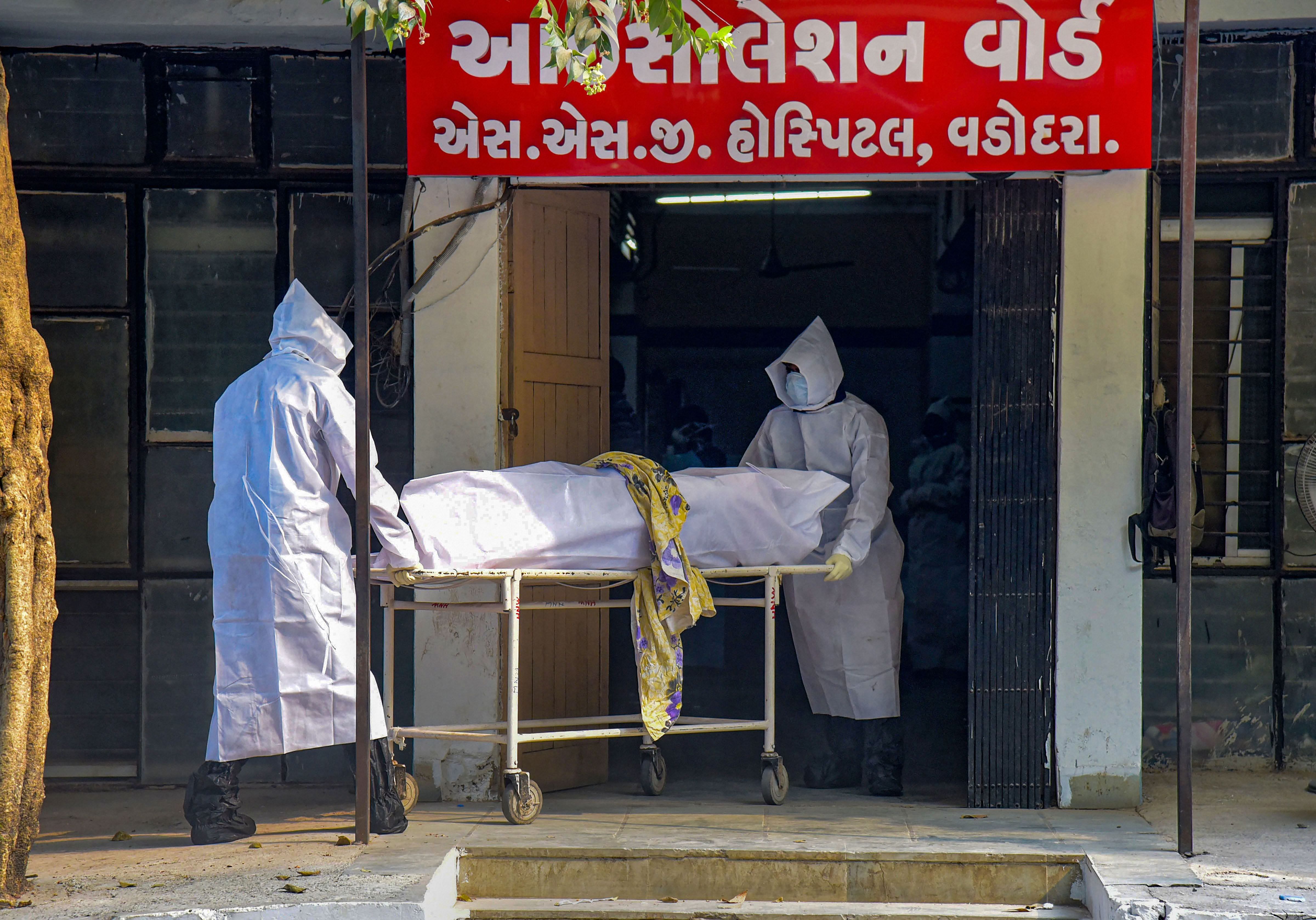 Medic staff wears protective suits and moves a dead body of coronavirus-affected outside an isolation ward in Vadodara. (Credit PTI file photo)