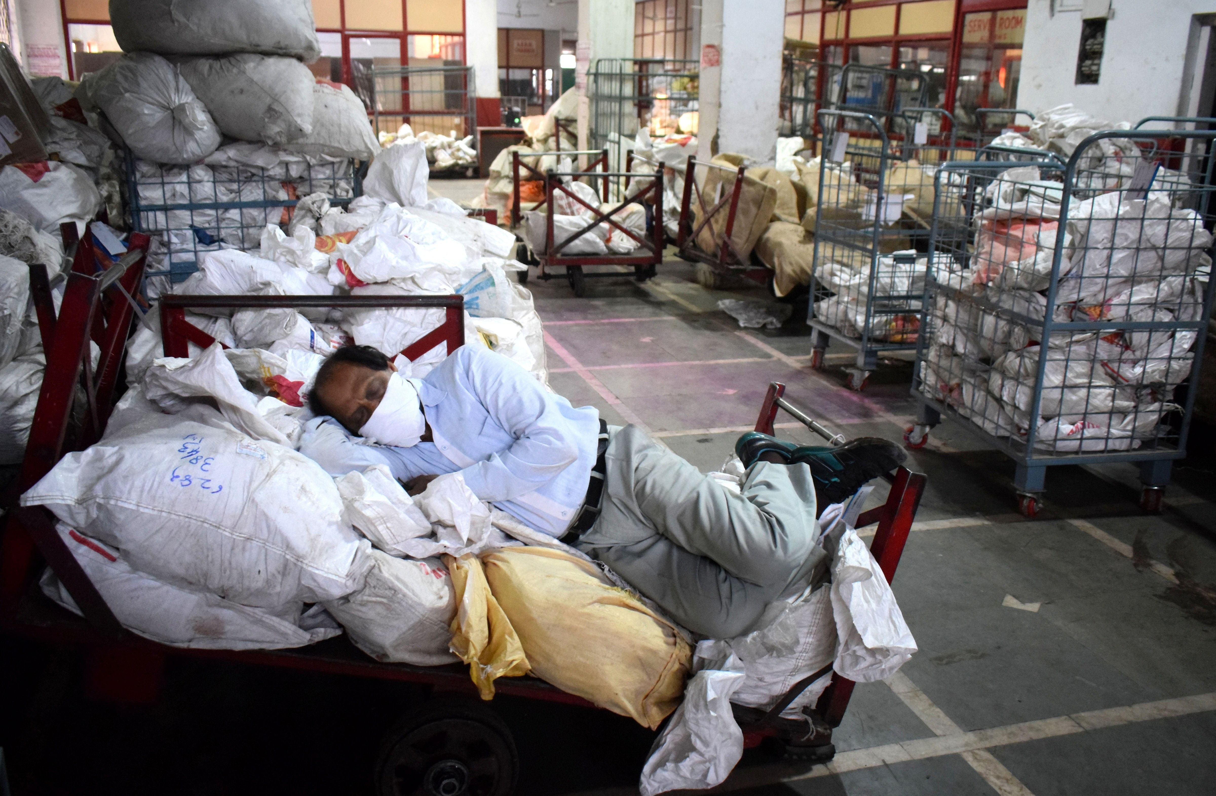 A man sleeps on parcel bags at Prayagraj Railway Station, on the second day of the nationwide lockdown. (Credit: PTI)