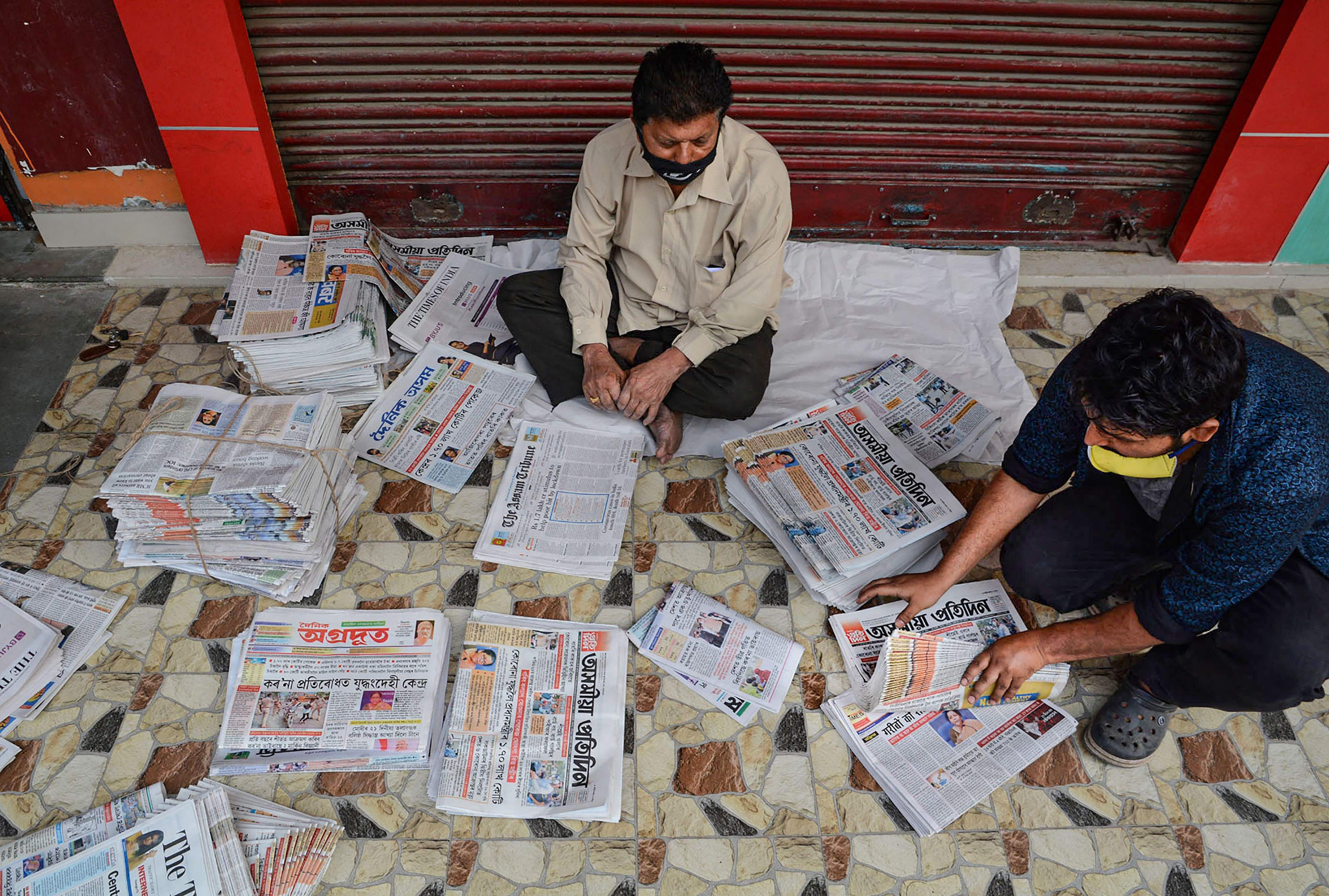 Vendors arrange different vernacular newspaper before delivering it to customers during the nationwide lockdown in Guwahati. (Credit: PTI)