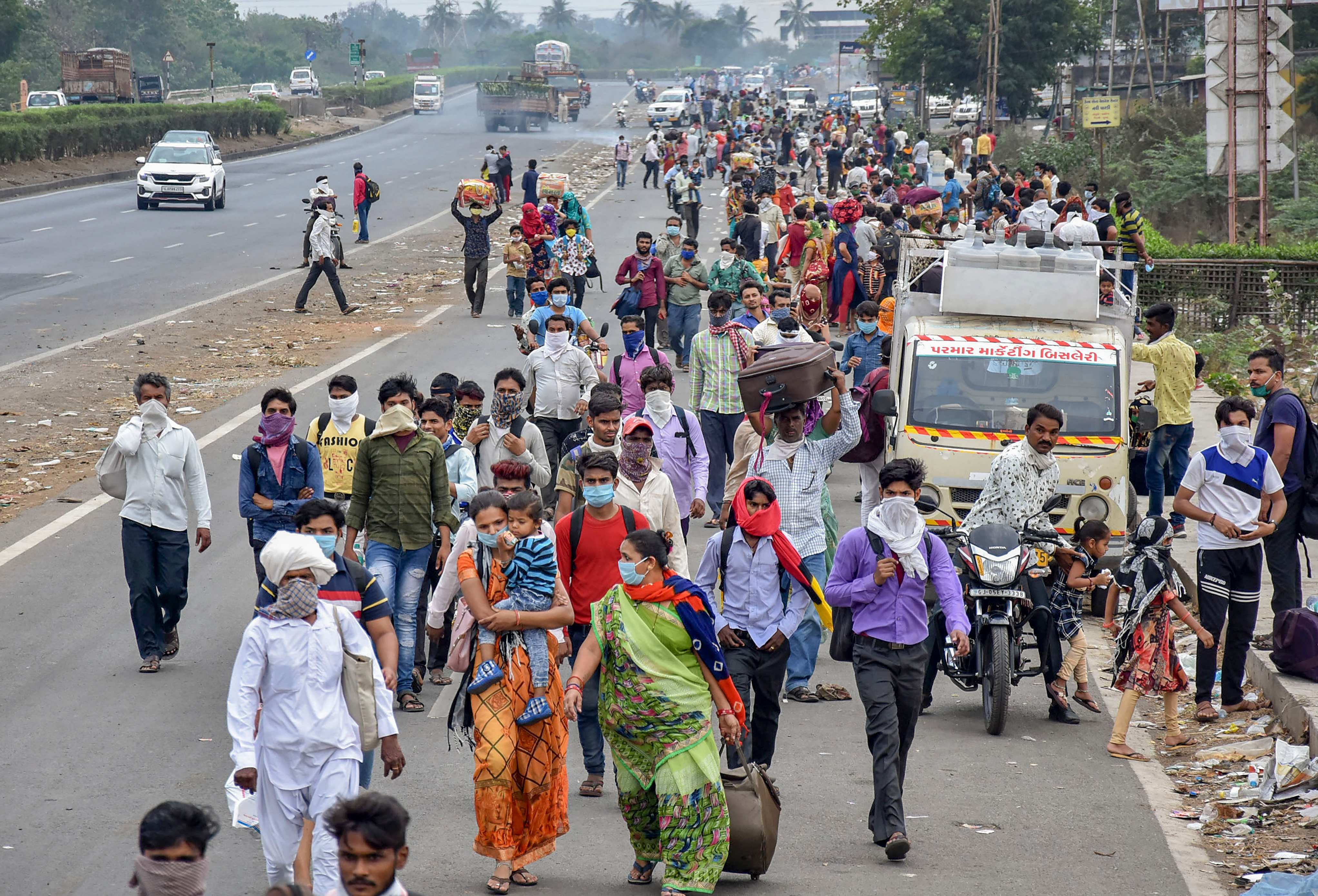 Surat: Migrant workers and their families walk on a road to return to their villages after the government imposed a 21-day nationwide lockdown. (Credit: PTI)