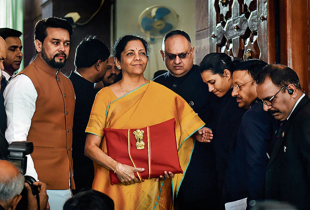 Union Finance Minister Nirmala Sitharaman, flanked by her deputy Anurag Thakur (to her right) and a team of officials, shows a folder containing the Union Budget documents as she poses for lensmen on her arrival at Parliament in New Delhi, Saturday, Feb. 1, 2020. (PTI Photo/Manvender Vashist)