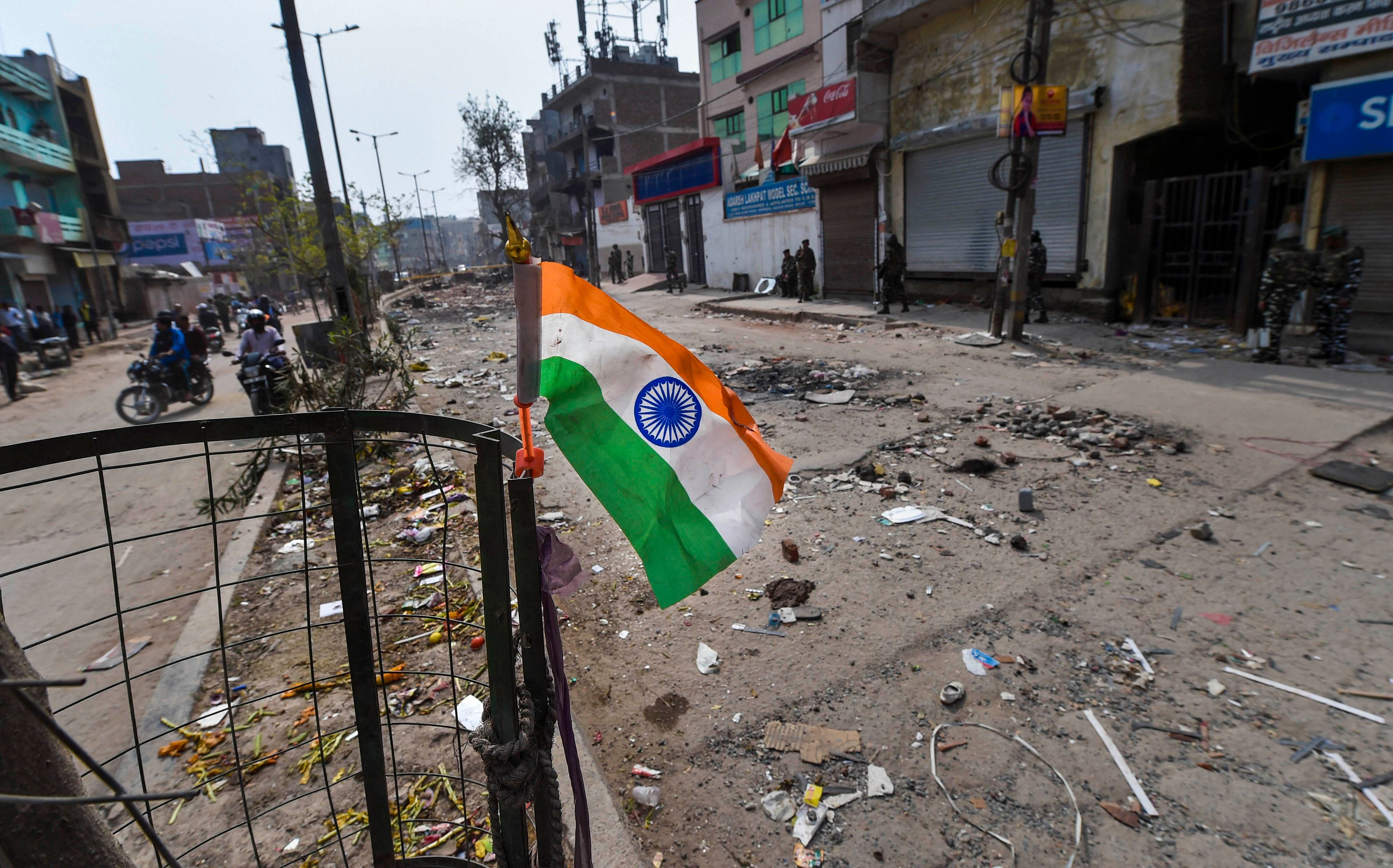 Security personnel stand guard at a closed market in a riot-affected area of northeast Delhi. (Credit: PTI)