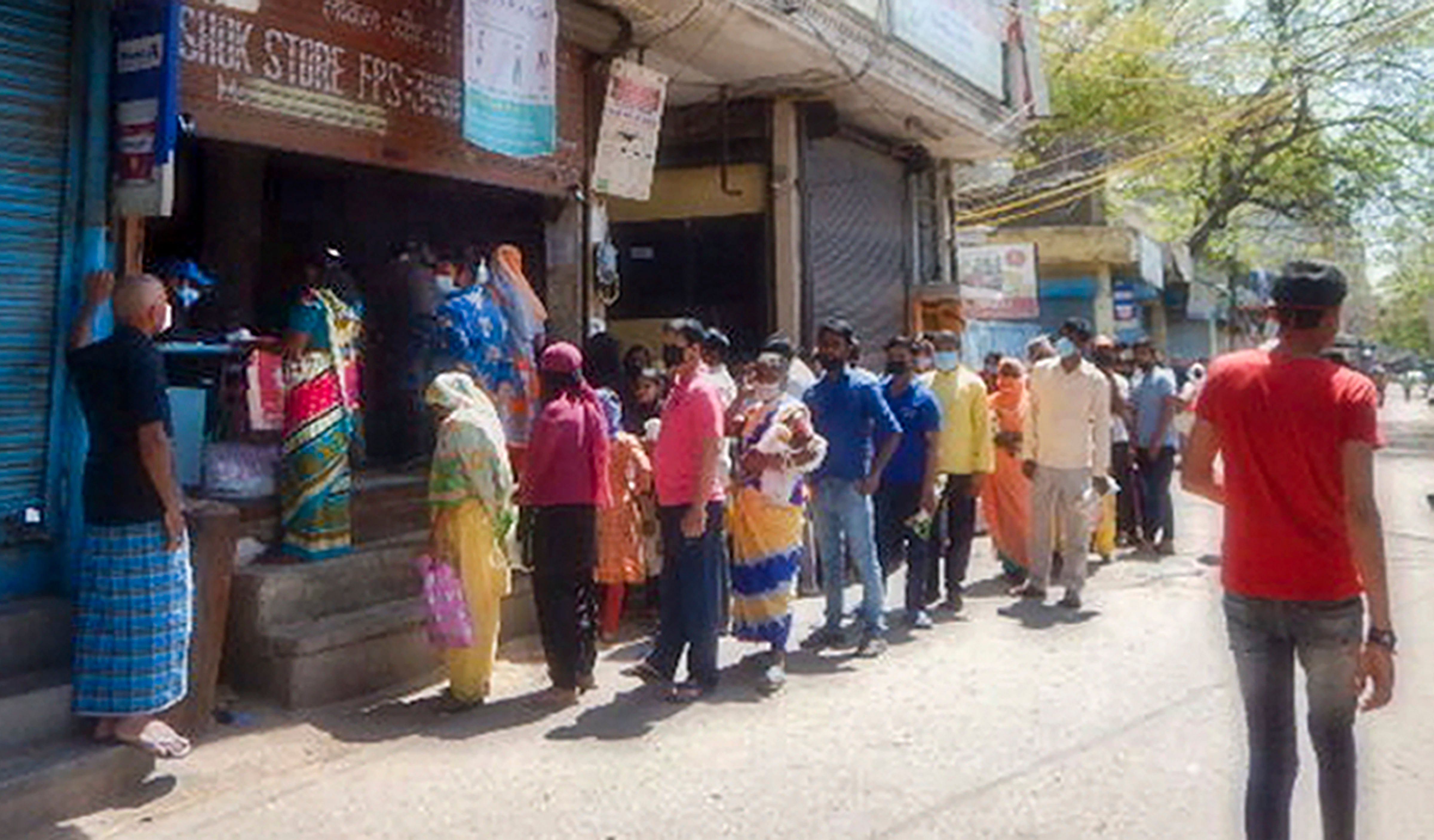 PDS beneficiaries stand in a queue before a ration depot to receive free 5kg grains under the Pradhan Mantri Garib Kalyan Yojana (PMGKY) during the nationwide lockdown amid coronavirus outbreak. (Credit: PTI)