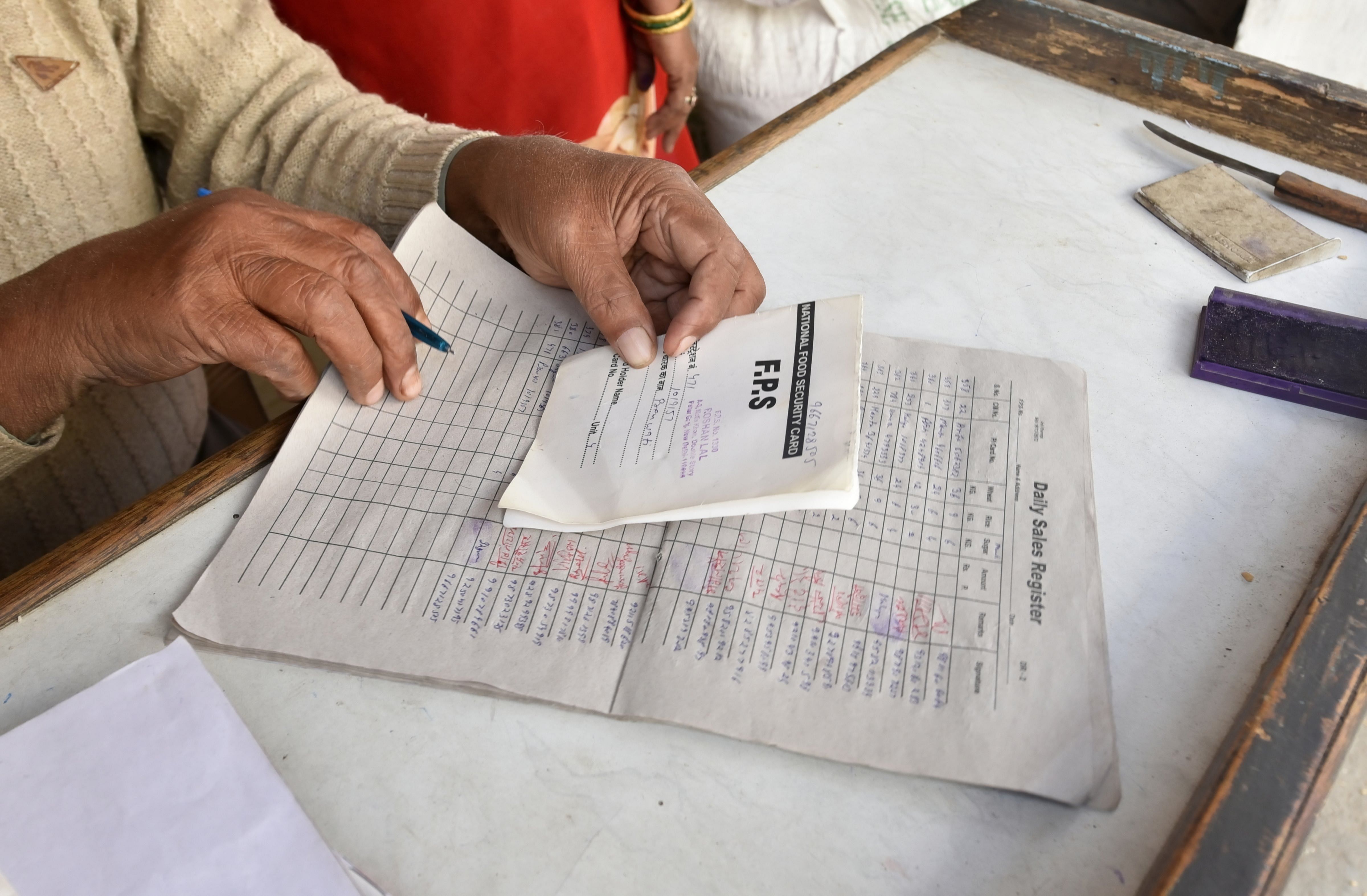  A shopkeeper checks a card of a beneficiary before giving free grains during a nationwide lockdown amid the coronavirus outbreak in New Delhi. (Credit: PTI)