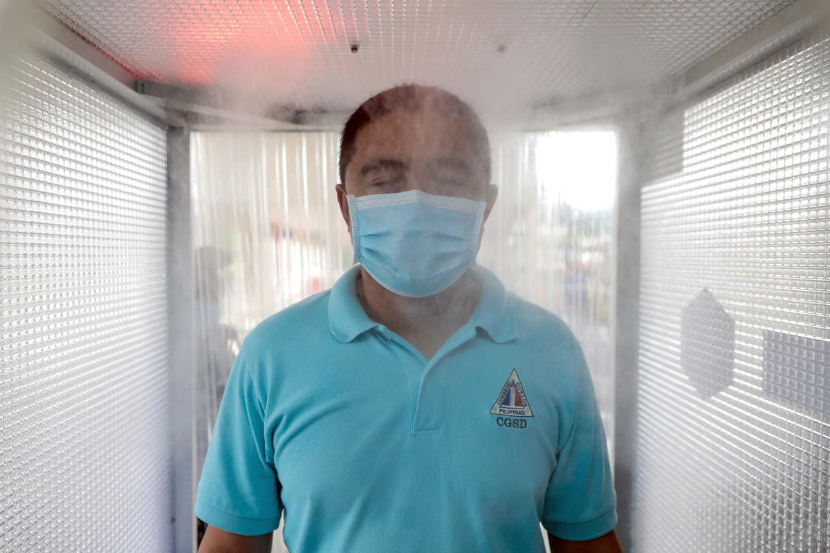A man wearing a face mask uses a disinfection booth that mists ethyl alcohol to contain the spread of coronavirus disease (COVID-19) in Quezon City, Metro Manila, Philippines. (Reuters photo)