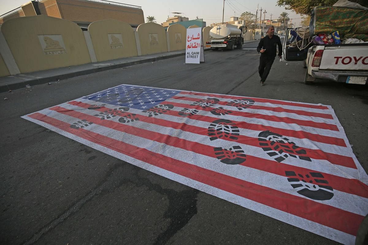 A mock US flag is laid on the ground for cars to drive on in the Iraqi capital Baghdad on January 3, 2020, following news of the killing of Iranian Revolutionary Guards top commander Qasem Soleimani in a US strike on his convoy at Baghdad international airport. AFP