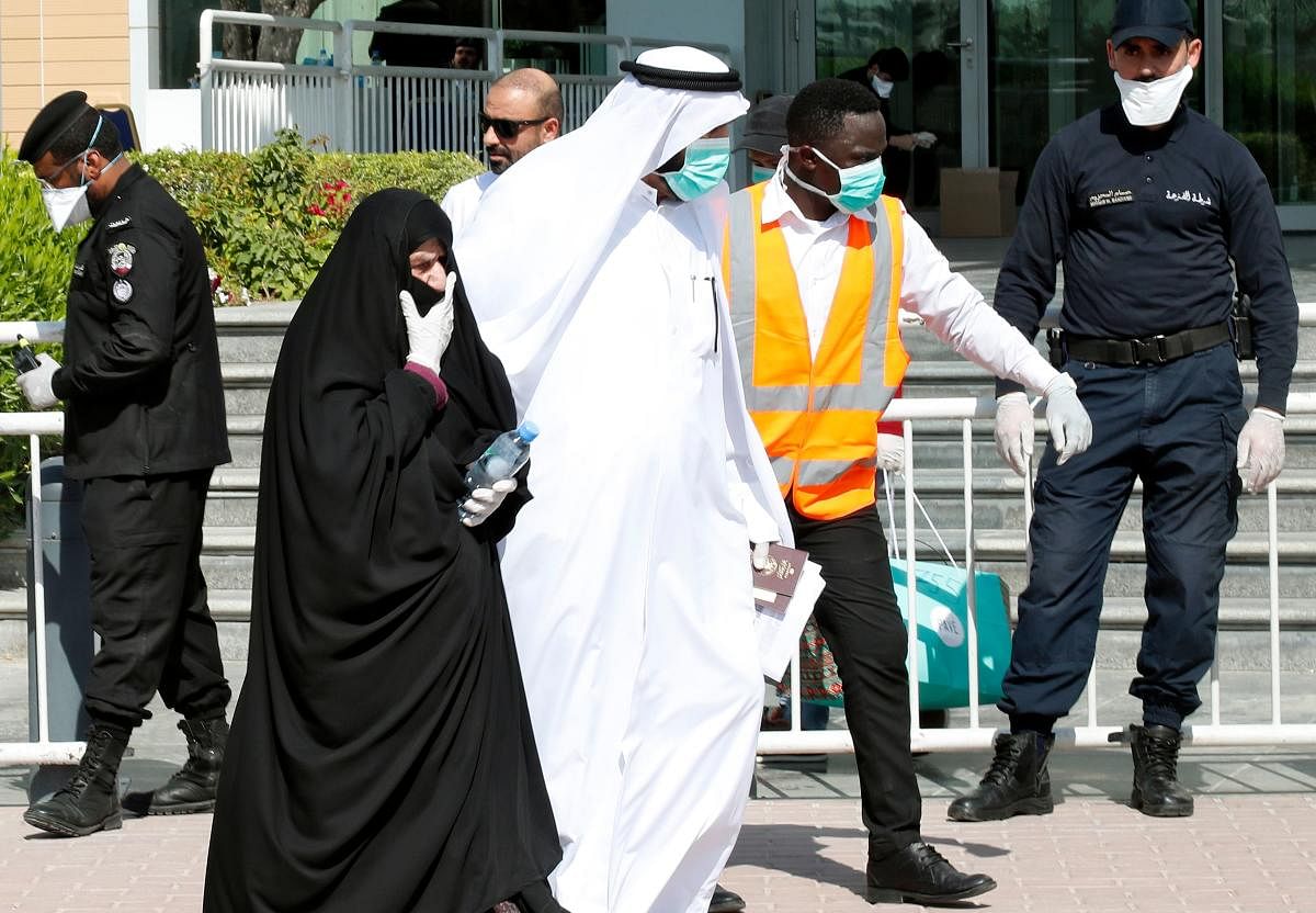 Qatari police stand outside a hotel in Doha as a medical worker walks alongside people wearing protective masks over fears of coronavirus (AFP Photo)