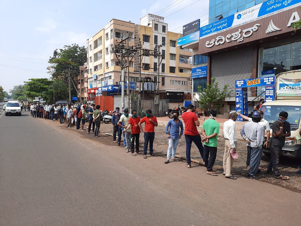 A long queue to buy booze from a liquor store in Belagavi on Monday. (Credit: DH Photo)