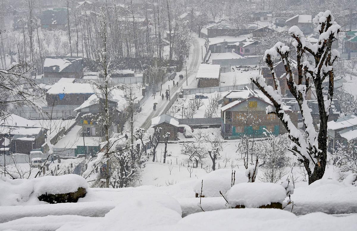 People walk on a snow-coverd road during snowfall on the outskirts of Srinagar. (PTI Photo)