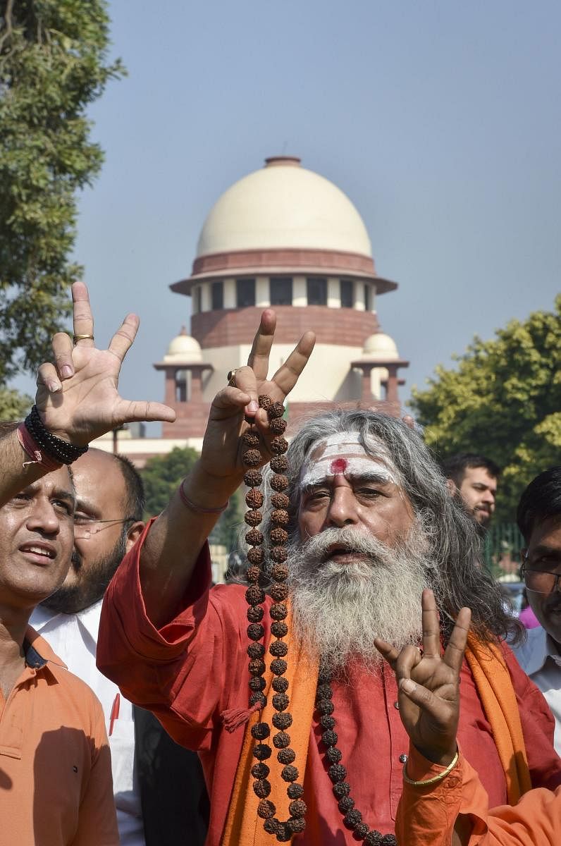A sadhu flashes the victory sign at the Supreme Court complex after the pronouncement of the Ayodhya case verdict, in New Delhi, Saturday, Nov. 9, 2019. (PTI Photo)