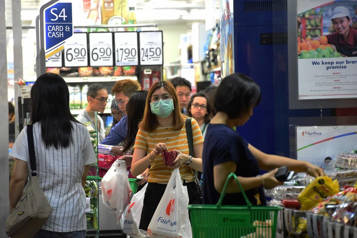 A woman wearing a facemask amid fears about the spread of the COVID-19 coronavirus shops at a supermarket in Singapore. AFP