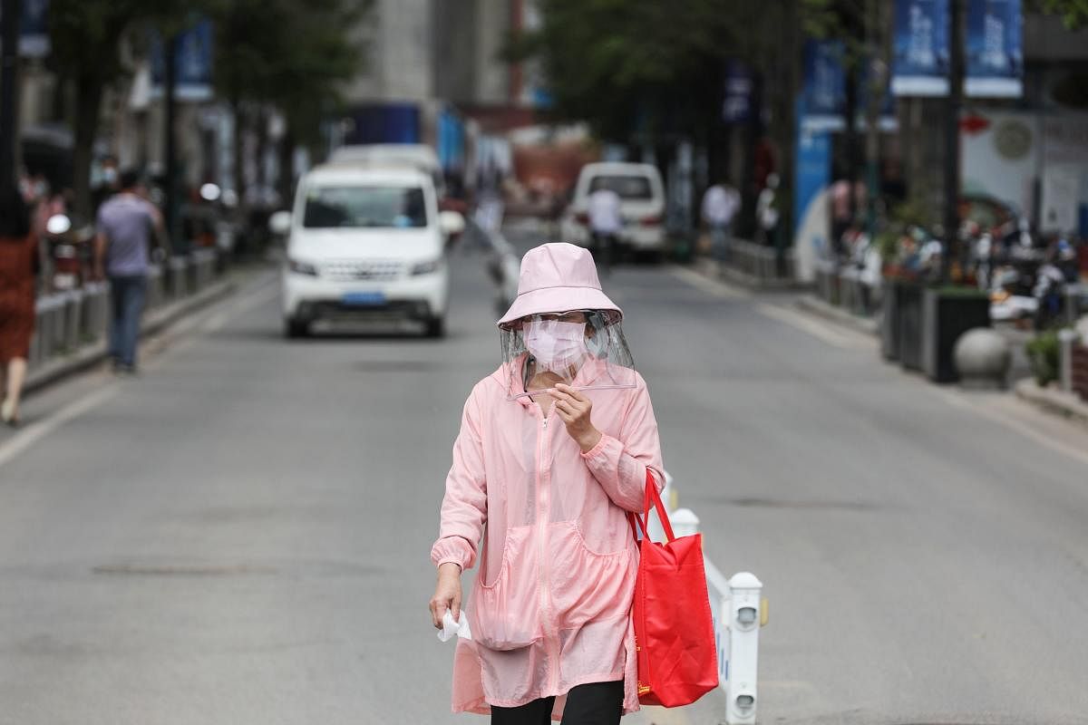 A woman wears a face shield as she walks along a street in Wuhan in China's central Hubei province. AFP