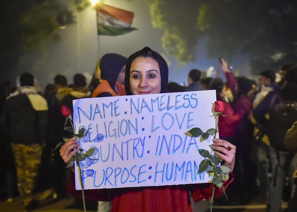 A protestor holds a placard and roses during a demonstration against the Citizenship (Amendment) Act, at Jantar Mantar. PTI