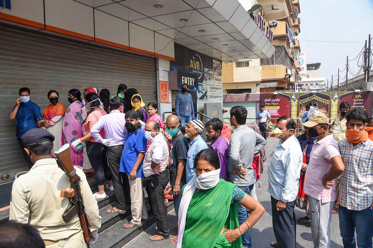 People wearing masks stand outside a grocery store to buy essential items during the nationwide lockdown imposed in the wake of coronavirus pandemic, in Patna, Wednesday, March 25, 2020.(PTI Photo)