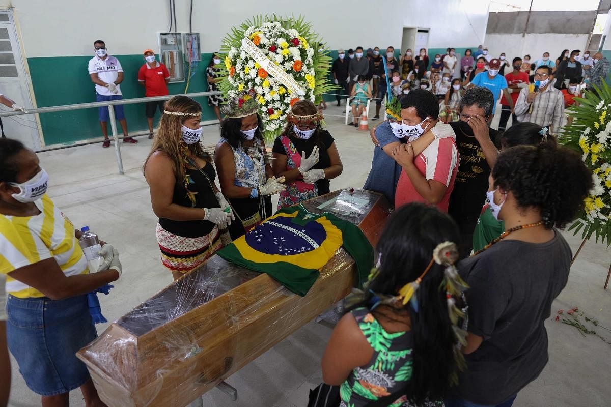 Indigenous from the Parque das Tribos community mourn besides the coffin of Chief Messias, 53, of the Kokama tribe who died victim of the new coronavirus, COVID-19, in Manaus, Brazil, on May 14, (AFP)