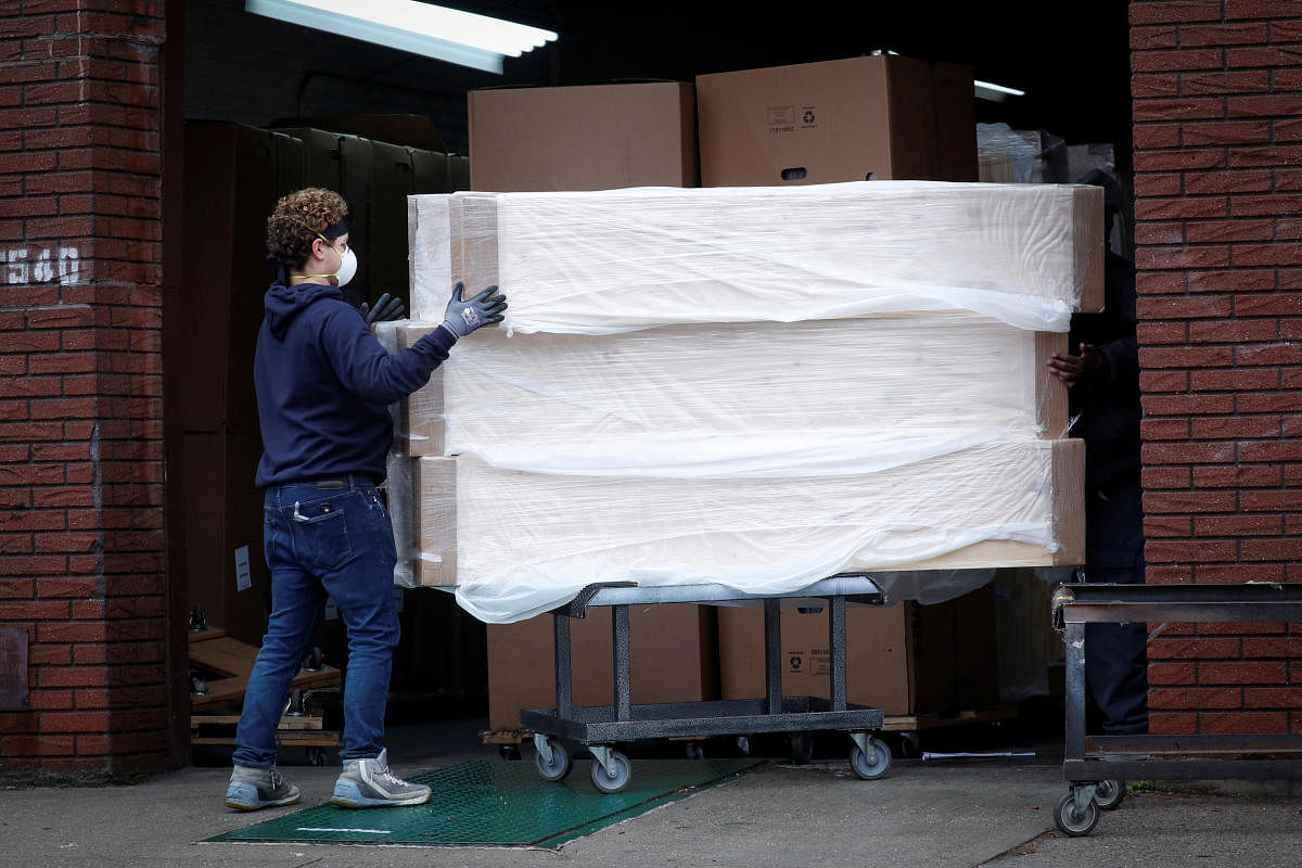 Workers move a stack new caskets at a warehouse during the outbreak of the coronavirus disease (Reuters Photo)