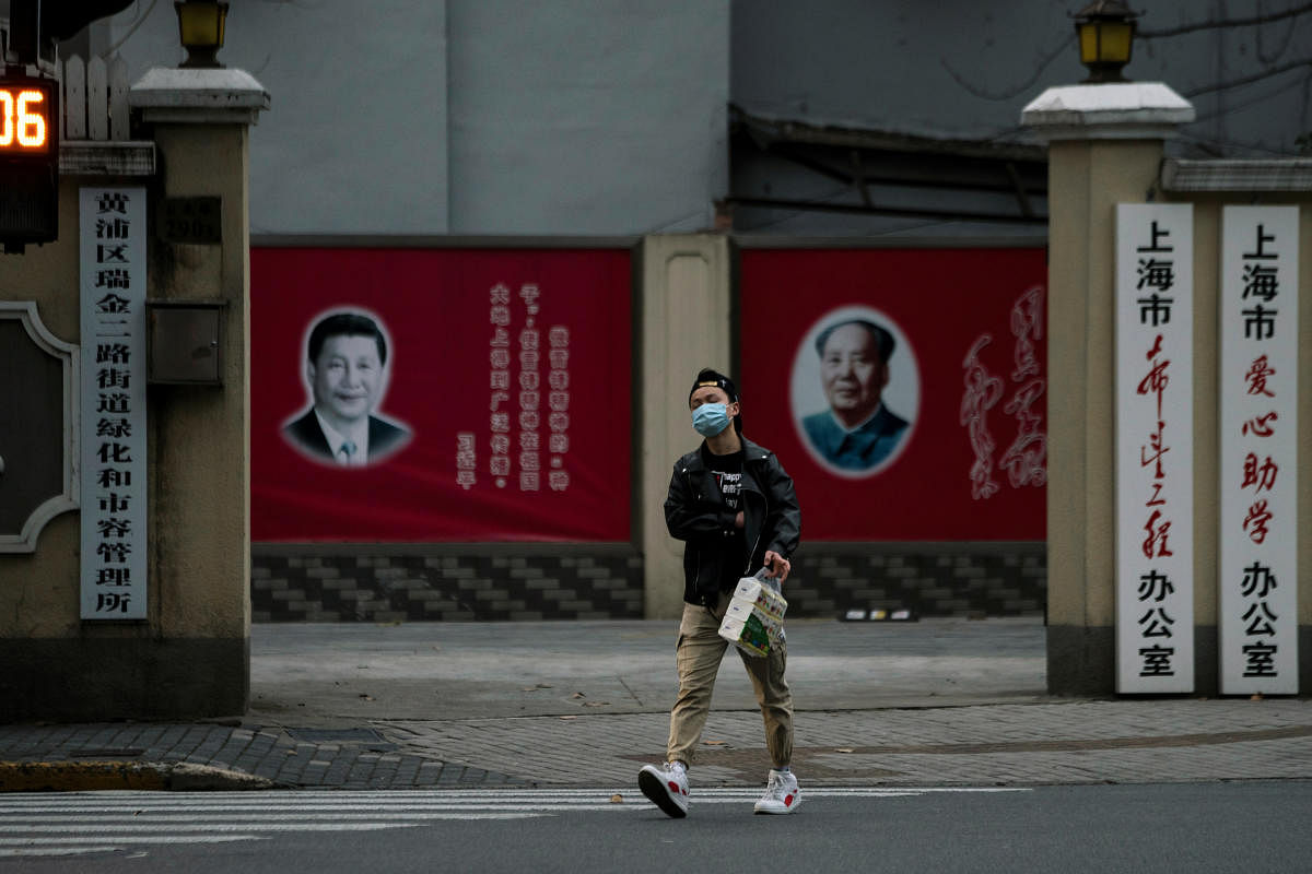 A man wearing a mask walks by portraits of Chinese President Xi Jinping and late Chinese chairman Mao Zedong as the country is hit by an outbreak of the novel coronavirus, on a street in Shanghai. Credit: Reuters Photo