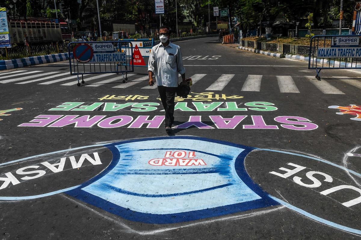 A man wearing a facemask walks on a road covered with paintings about precautions to follow during a government-imposed nationwide lockdown as a preventive measure against the COVID-19 coronavirus, in Kolkata on April 7, 2020. Credit: AFP Photo