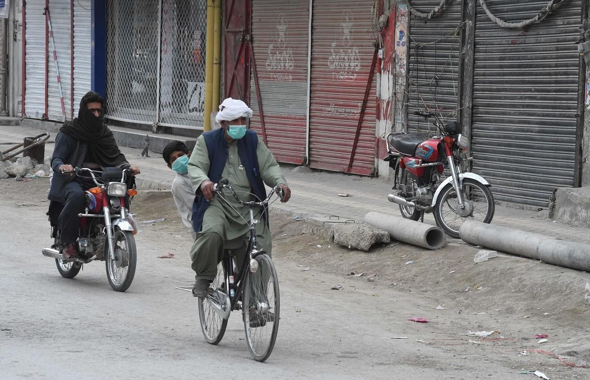 Commuters wearing facemasks as a preventive measure against the COVID-19 coronavirus make their way past closed shops in Quetta on March 22, 2020. Credit: AFP Photo