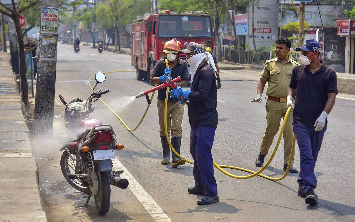 SDRF and Fire brigade officials spray disinfectant on a bike in the wake of the coronavirus, in Nagaon. PTI