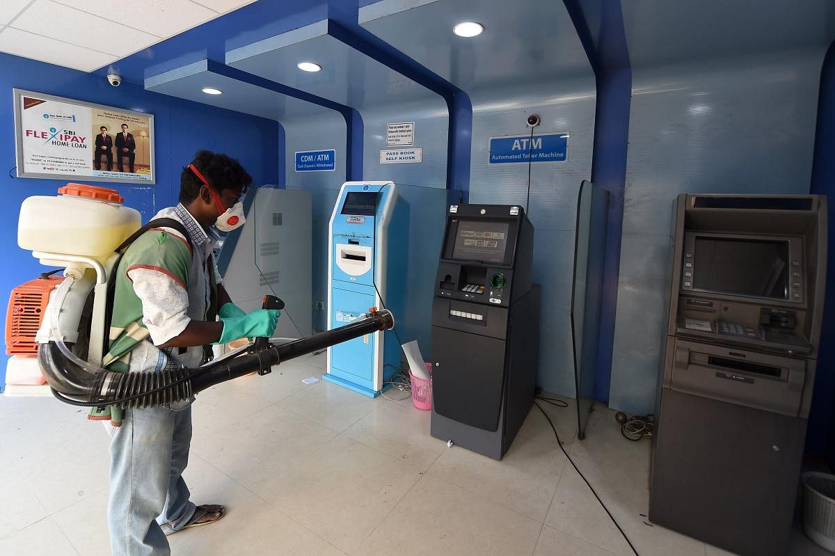  A worker sprays disinfectants on ATM machines during the coronavirus lockdown in Chennai. PTI/File