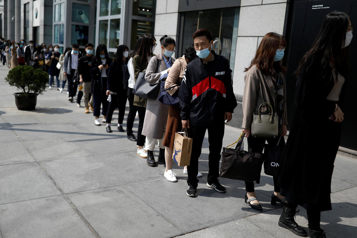People wearing face masks, following the coronavirus disease (COVID-19) outbreak, make a line to enter an office building in Beijing. Reuters