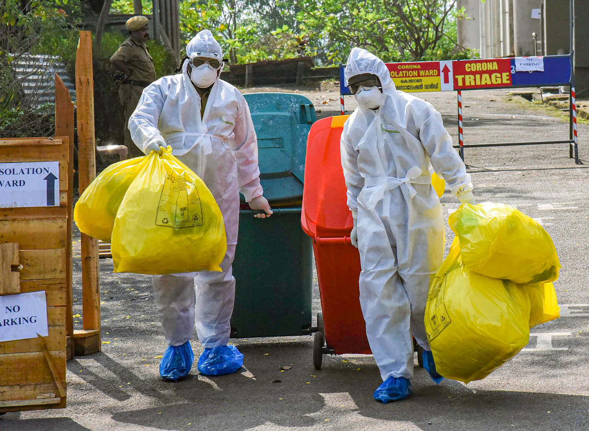 Medical staff, wearing protective suits, hold medical waste as they exit the Special Isolation Ward set up to provide treatment to novel coronavirus patients at Kochi Medical college. PTI
