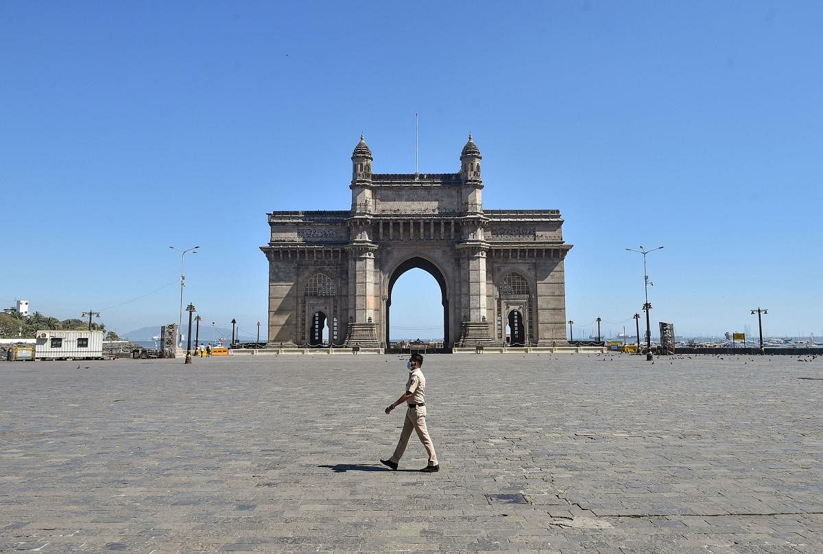 A policeman wearing protective mask in the wake of coronavirus pandemic, walks past a deserted Gateway of India. PTI