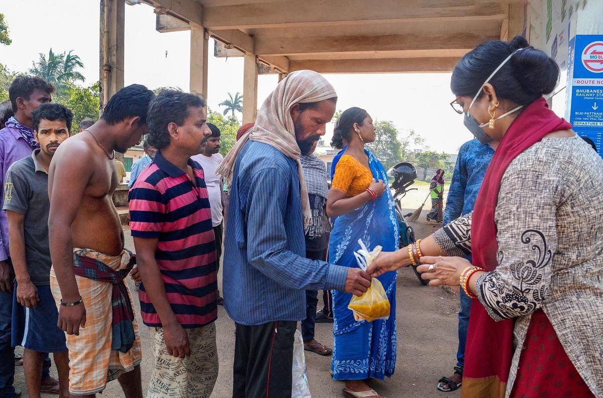 A volunteer distributes food packets among poor people during a lockdown in the wake of the coronavirus. PTI