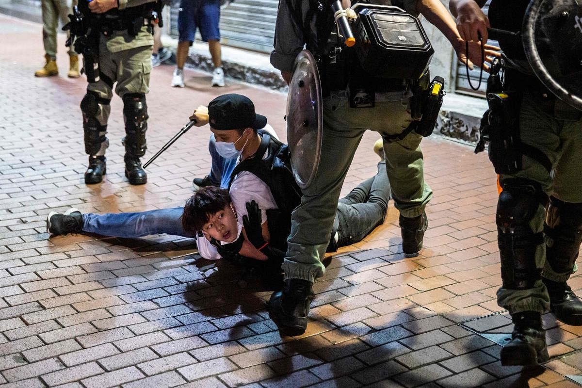 A pro-democracy demonstrator (C) is held on the ground before getting arrested by undercover police during a protest (AFP Photo)