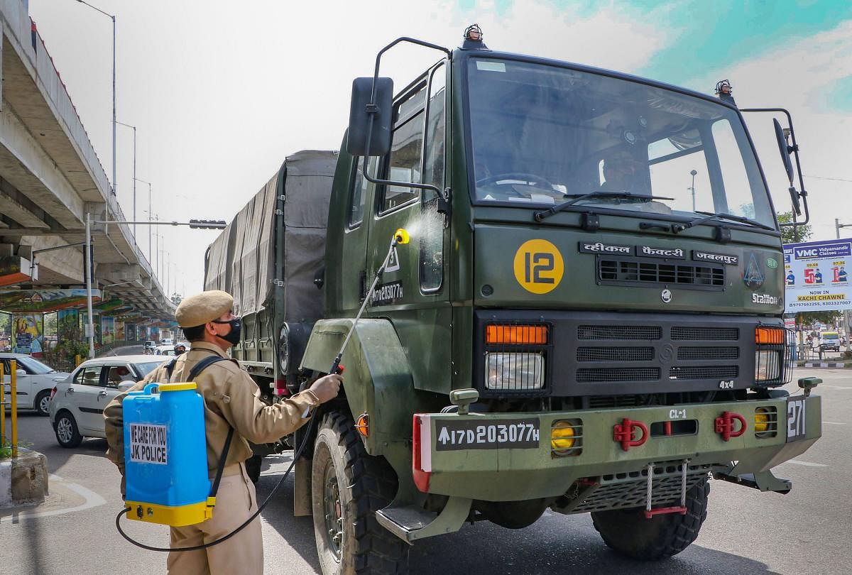 A police official sprays disinfectant on an army truck during a nationwide lockdown, imposed in the wake of coronavirus pandemic in Jammu (PTI Photo)