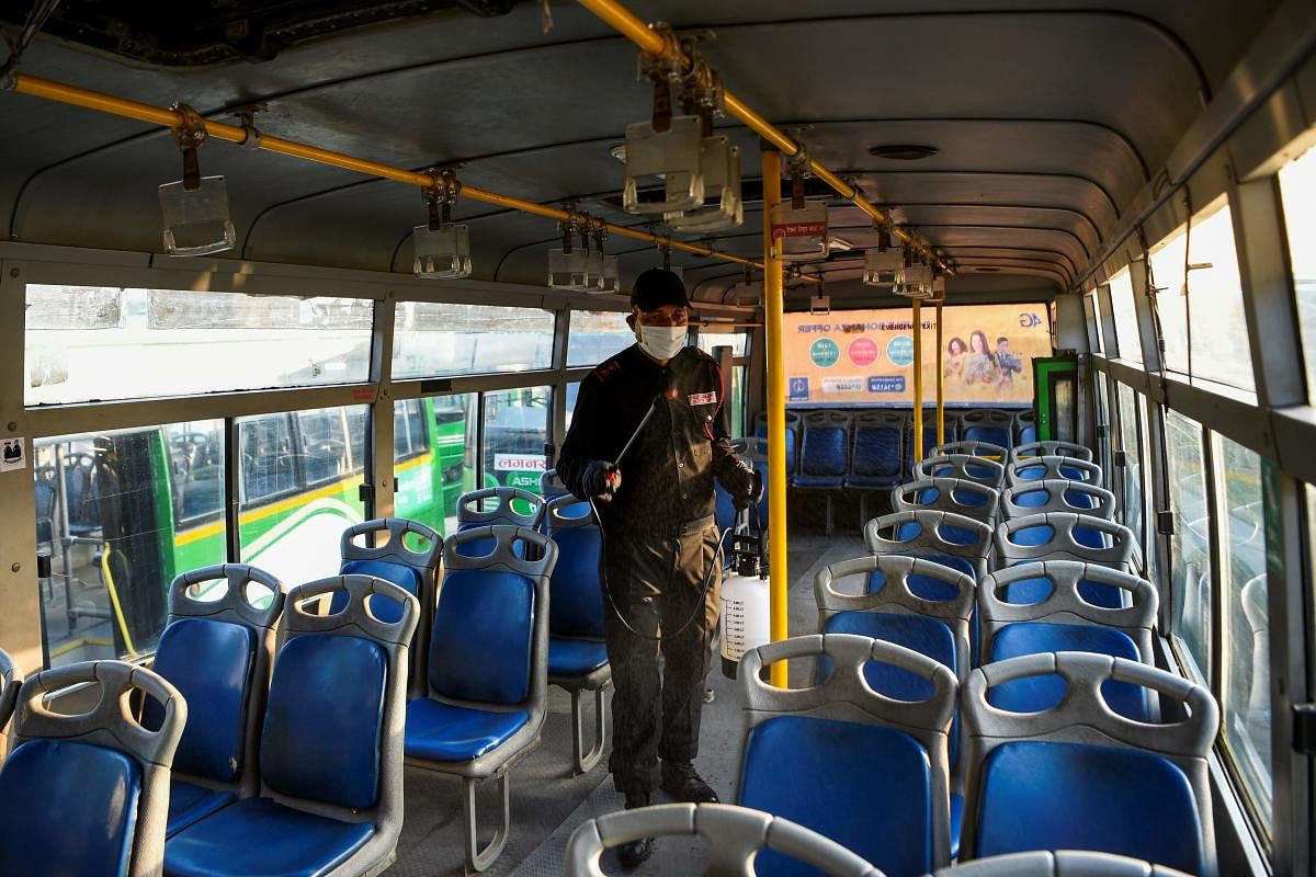 A worker sprays disinfectant to sanitize a public bus as a preventive measure against the COVID-19 coronavirus at a bus depot in Kathmandu (AFP Photo)