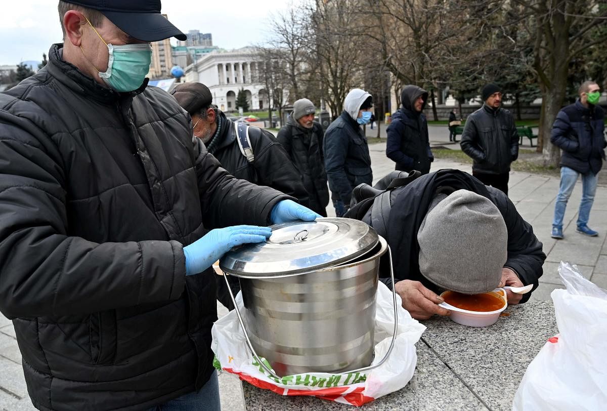 Homeless and vulnerable people wearing face masks, amid concerns over the spread of the novel coronavirus COVID-19, eat a free meal distributing by charity activists (AFP Photo)