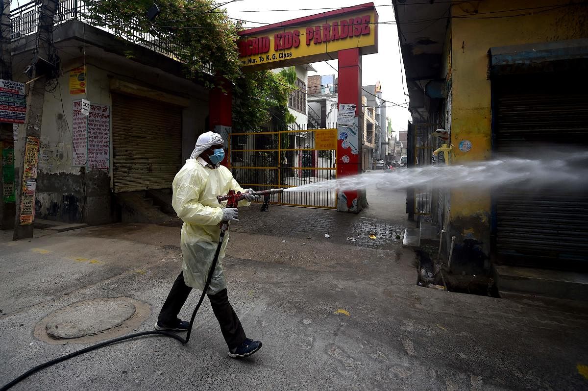 A municipal worker sprays disinfectant solution to sanitise an area (AFP Photo)