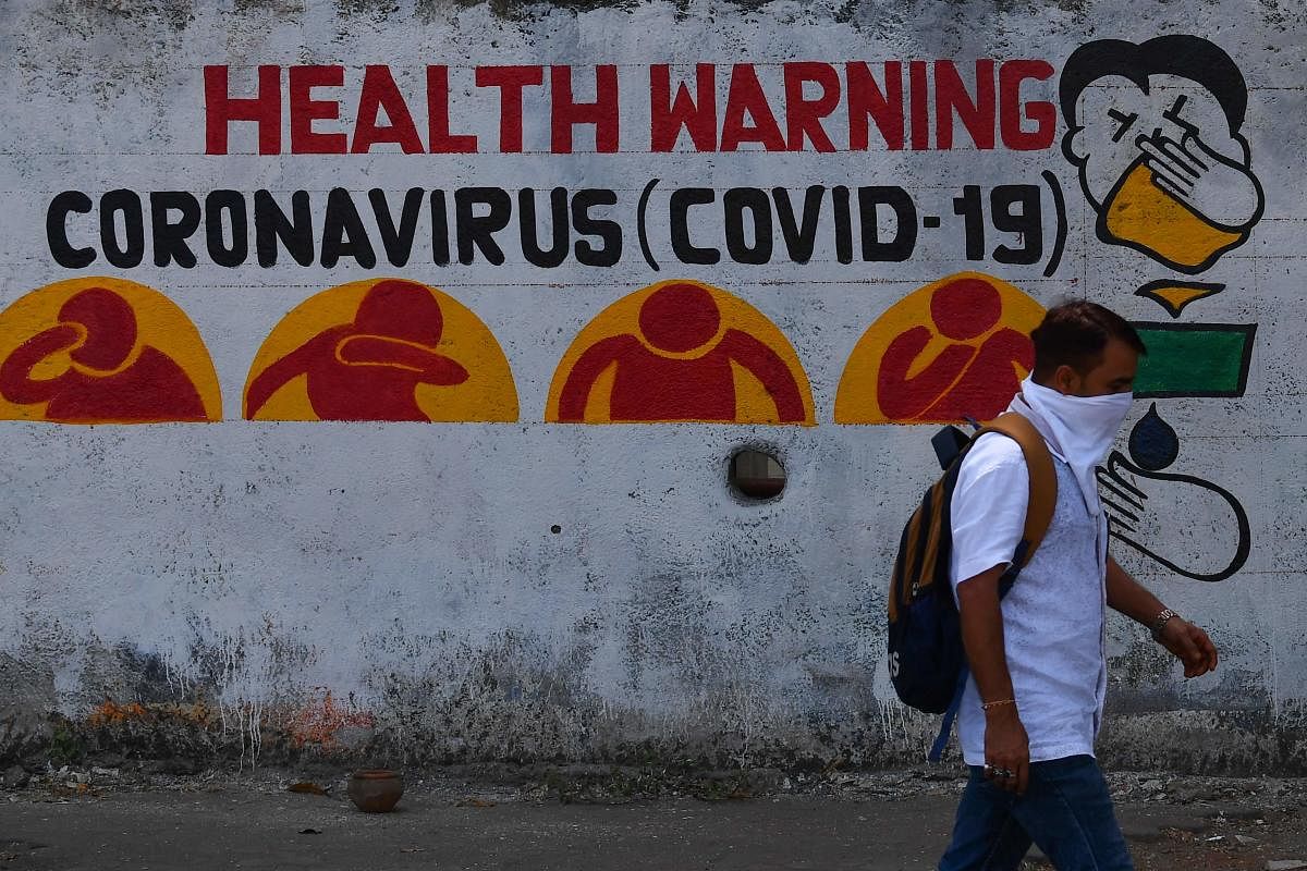 A pedestrian wearing a facemask as a preventive measure against the COVID-19 novel coronavirus walks past an awareness graffiti in Mumbai on March 23, 2020. (Photo by Indranil MUKHERJEE / AFP)