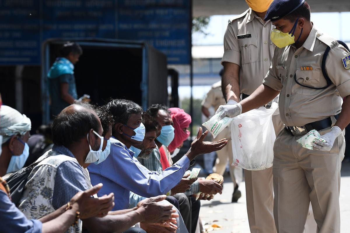 Central Reserve Police Force (CRPF) personnel distribute food to homeless people during a government-imposed nationwide lockdown as a preventive measure against the spread of the COVID-19 novel coronavirus in New Delhi on March 30, 2020. (Photo by Prakash SINGH / AFP)