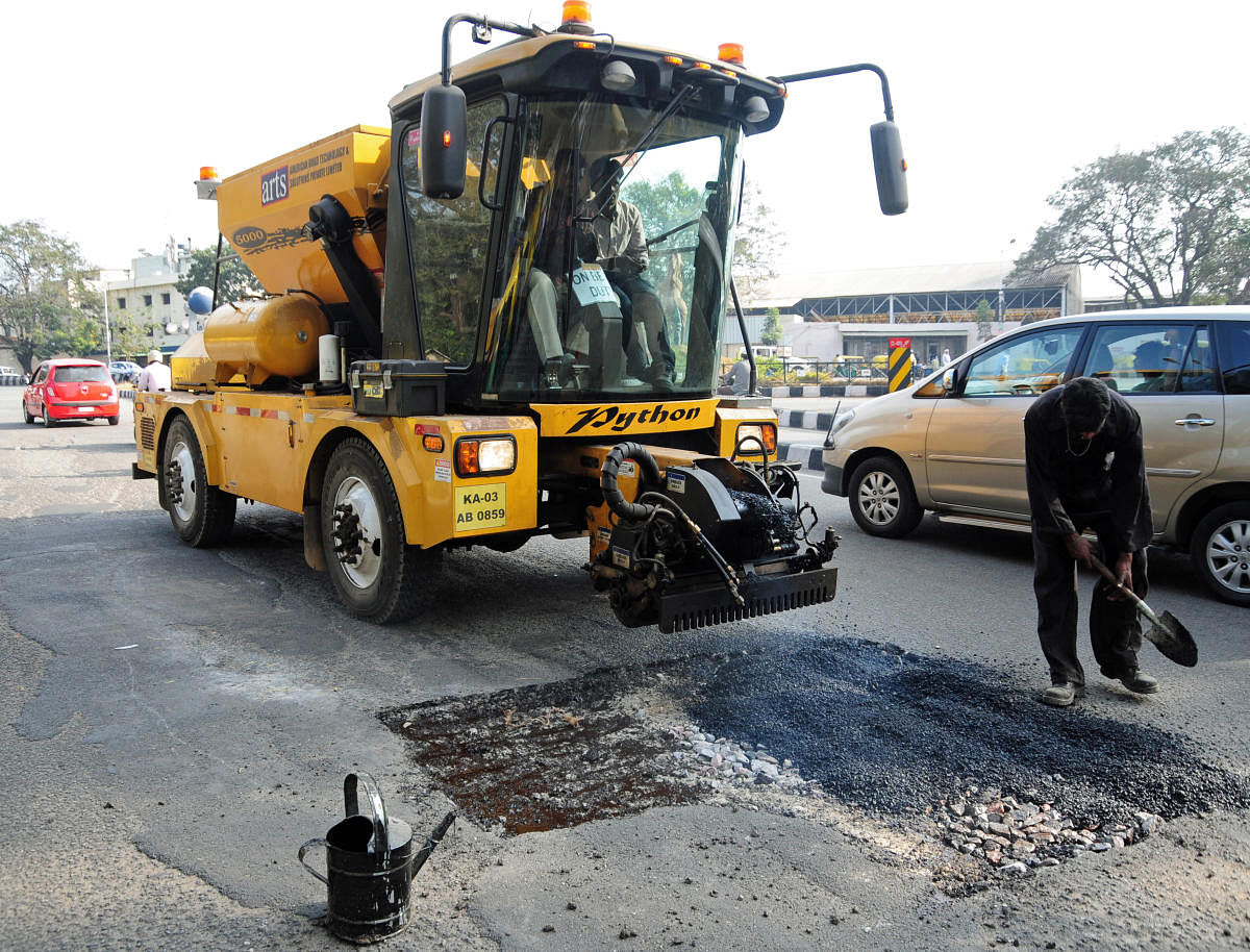 BBMP employees seen busy with filling potholes by using new pothole filling machine 'Python 5000' an product of American Road Technology & Solutions Private limited at busy Race Cource road in Bangalore on Friday afternoon. Photo by Satish Badiger