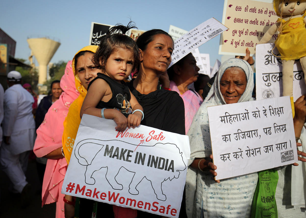 A girl holding a placard is carried by her mother as they attend a protest against the rape of an eight-year-old girl in Kathua, near Jammu, a teenager in Unnao, Uttar Pradesh, and an eleven-year-old girl in Surat, Gujarat, in Ahmedabad, India, April 18,
