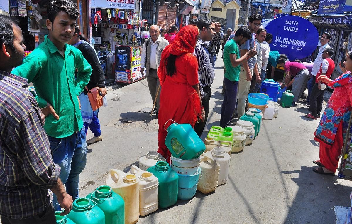 People stand in a queue to collect water from a tanker, as the city faces acute shortage of drinking water, in Shimla on Tuesday. PTI
