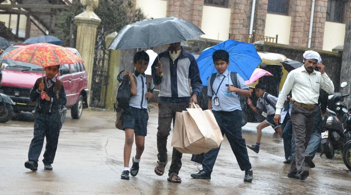 Children face showers on their way to school in Madikeri.