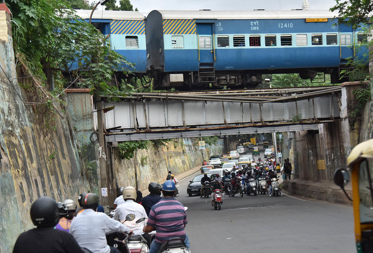 Two-wheelers wait for a train to pass in Bengaluru. (DH File Photo/ Janardhan B K)