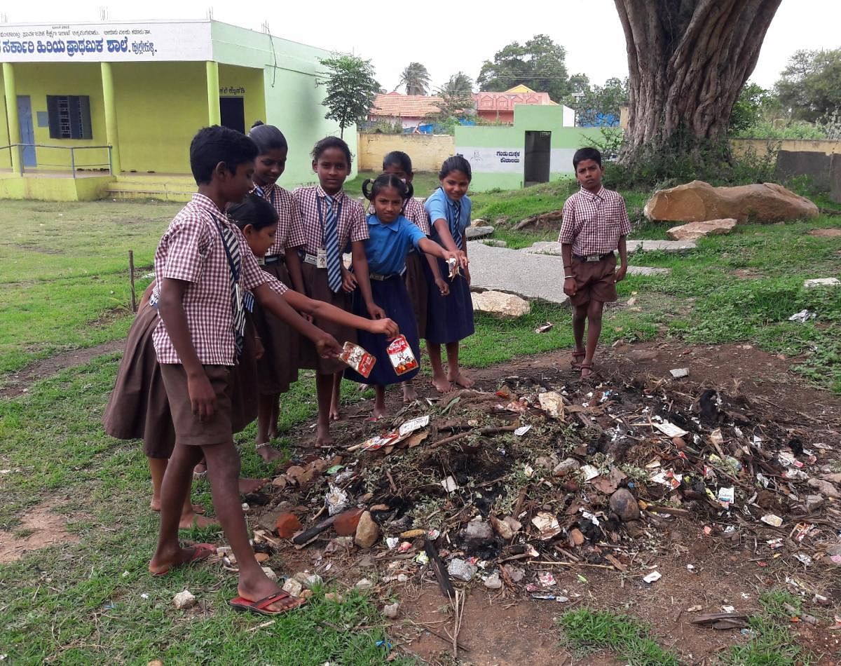 Students from the government school at Hullehalli collect liquor sachets from the school and gram panchayat premises.