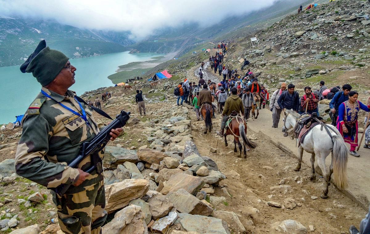 Security personnel look on as a batch of pilgrims are on their way towards the holy cave shrine of Amarnath, in Sheshnag Lake. PTI Photo