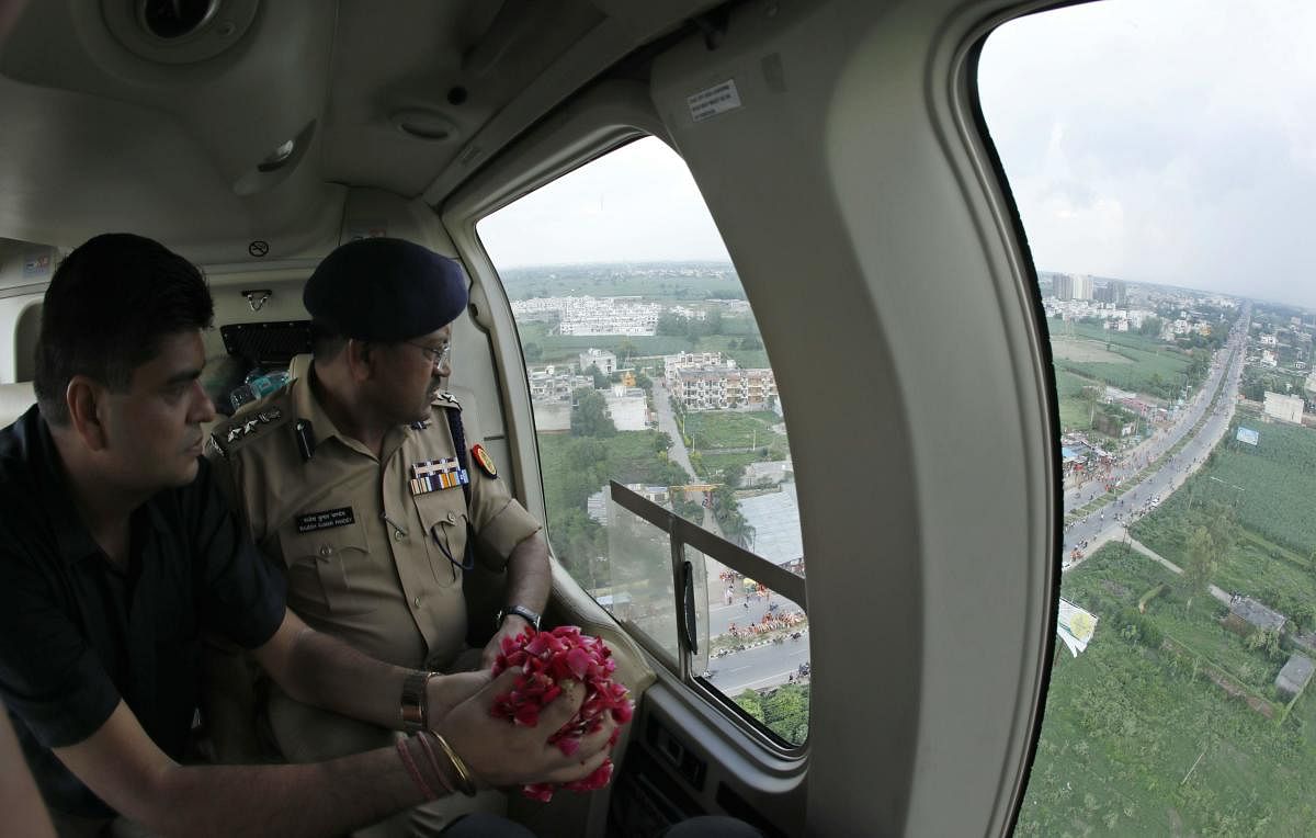 Meerut District Magistrate Anil Dhingra (L) and Senior Superintendent of Police Rajesh Kumar Pandey (R) prepare to sprinkle rose petals over "Kanwariyas" during an aerial inspection, in Meerut on August 8, 2018. AFP