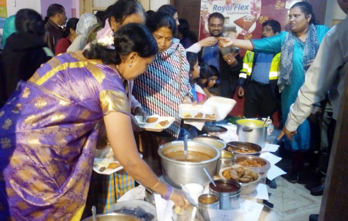 People relish traditional delicacies of Aati month, at the CSI Shanti Church premises in Madikeri on Sunday.