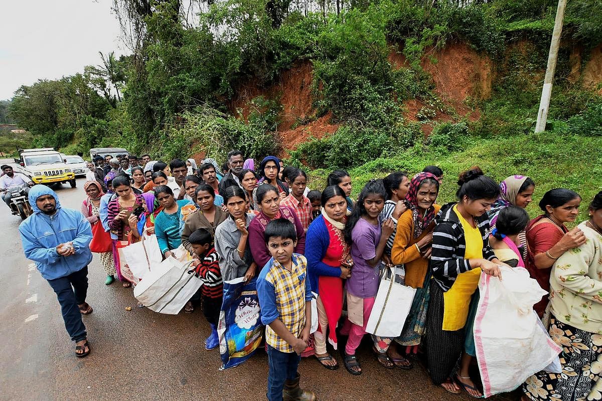 Kodagu: Flood-affected people queue to receive relief material near a relief camp in Kadagu, Karnataka on Tuesday, Aug 21, 2018. (PTI Photo)