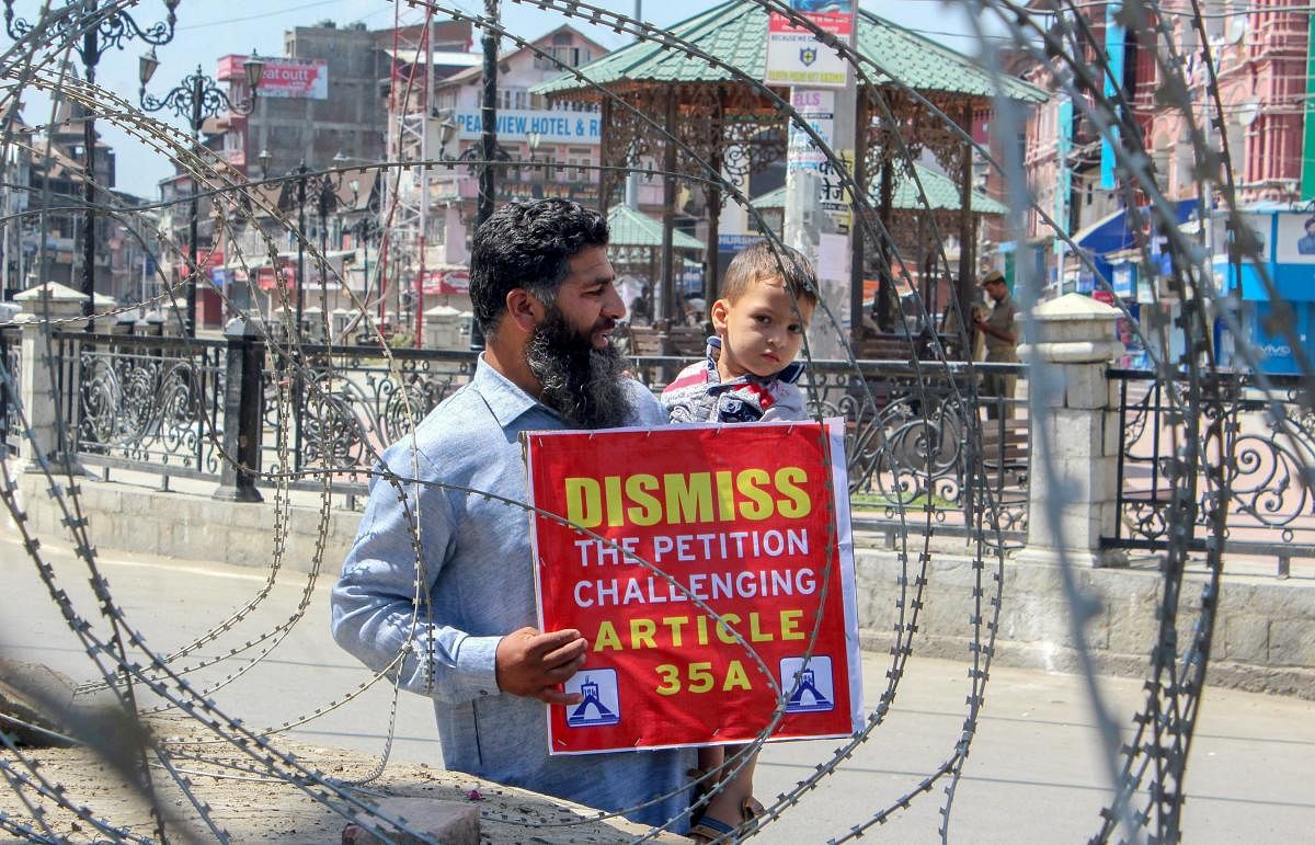 A man displays a placard during a protest march against the petitions challenging the validity of Article 35A, in Srinagar. PTI