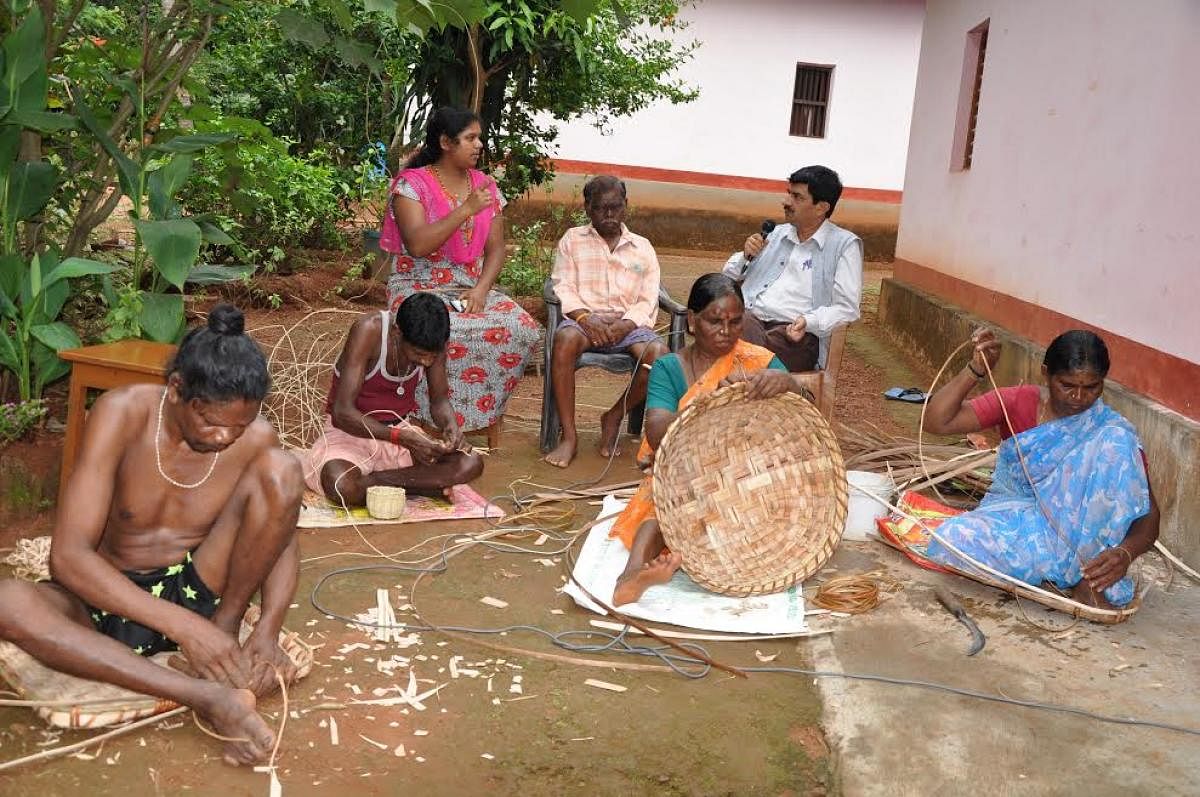 Members of Koraga community engaged in weaving baskets. 